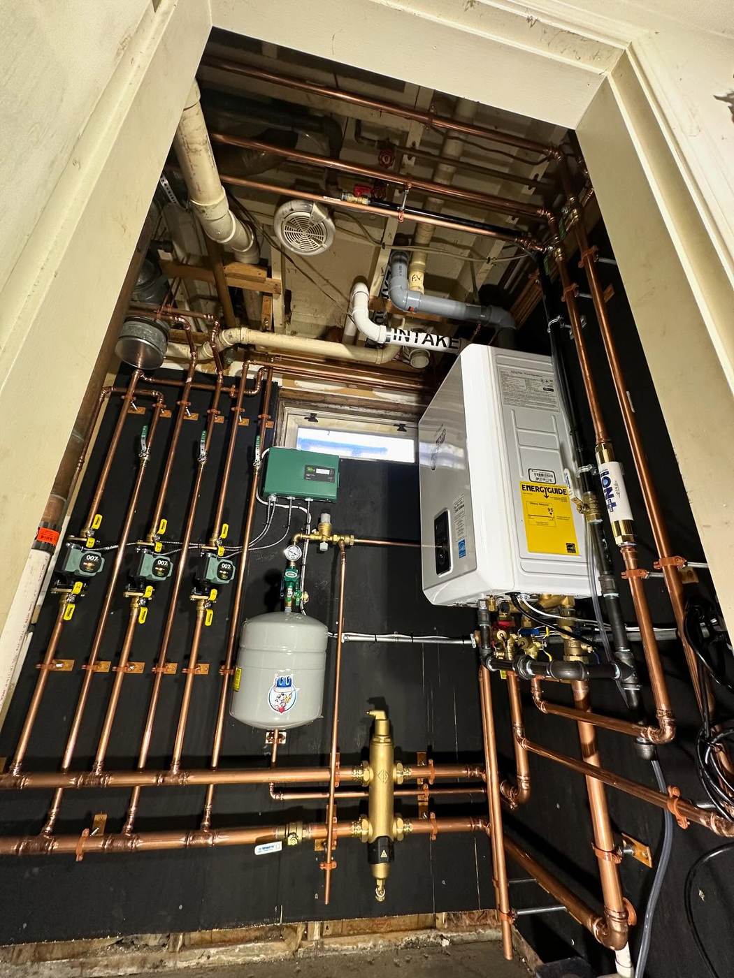 Hydronic piping on a black-painted board by J.Sar Plumbing